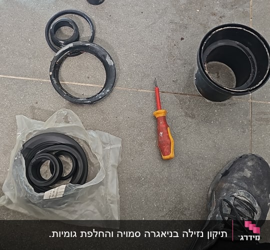 כלי עבודה וחלקי צנרת על רצפה אפורה